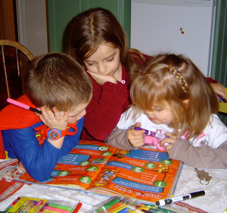 Three children reading a book. Copyright Gretta Schifano