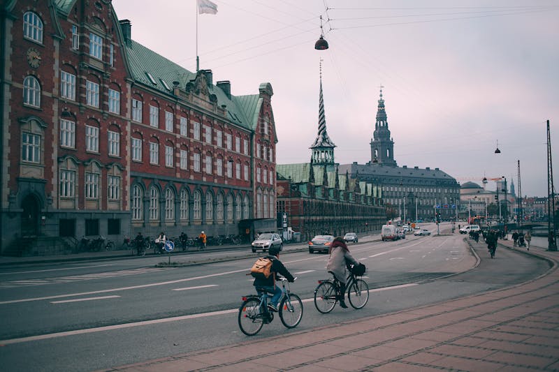 Cyclists along Copenhagen embankment with Christiansborg palace
