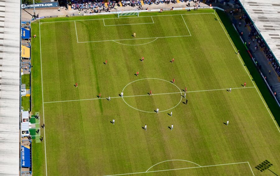 Aerial view of football match in sunlit stadium