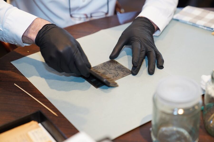 Art conservator using fine brush on painting canvas