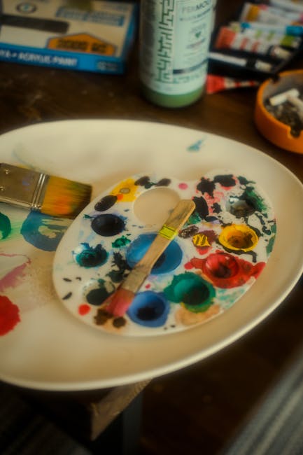 Artist palette with paints and brush in studio