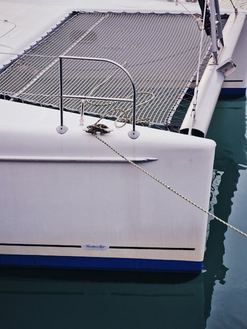 Person relaxing on catamaran net over blue ocean water
