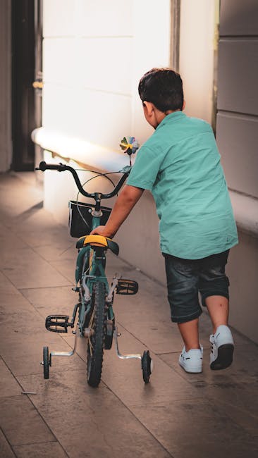 Young child learning to ride a bicycle with training wheels