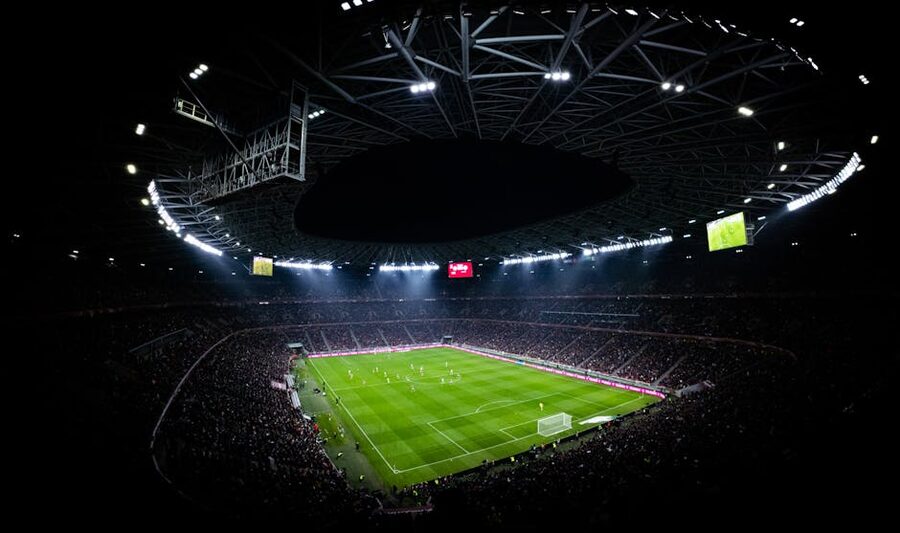 Football match in progress under stadium floodlights at night