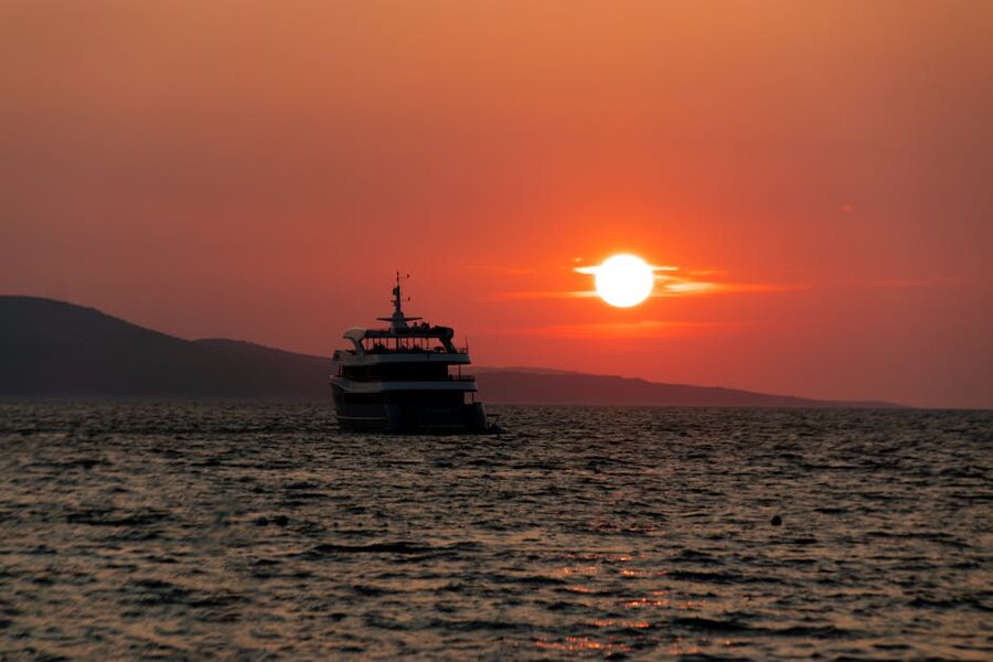 Boat cruising on Mediterranean sea at sunset with orange sky